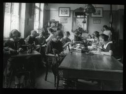 "Töchterheim Sihlwartheim, Zürich", junge Frauen, versammelt in einem Raum des Heims, möglichweise während einer Nähstunde, viele am nähen, einige am lesen und zeichnen, um 1930