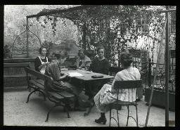 "Marthahaus, Zürich", fünf Frauen sitzen auf der Terrasse auf Bänken und Stühlen am Tisch, lesen und unterhalten sich, um 1930