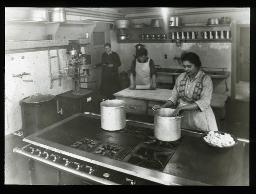 "Zürich, Neues Töchterheim", drei Frauen in der Küche, vermutlich am Zubereiten einer Mahlzeit, eine weitere mit Wallholz, um 1930