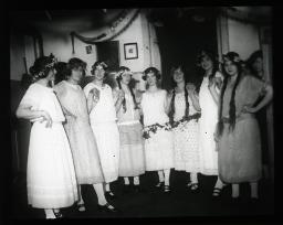 "Zürich, Töchterheim Jakobstrasse", mehrere junge Frauen, verkleidet mit Kleidern und Blumen, möglicherweise vor einer Theater- oder Musikaufführung, um 1930
